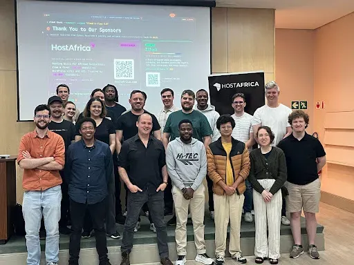 Clawd and Claws attendees in a group photo in front of a screen thanking HostAfrica as a sponsor