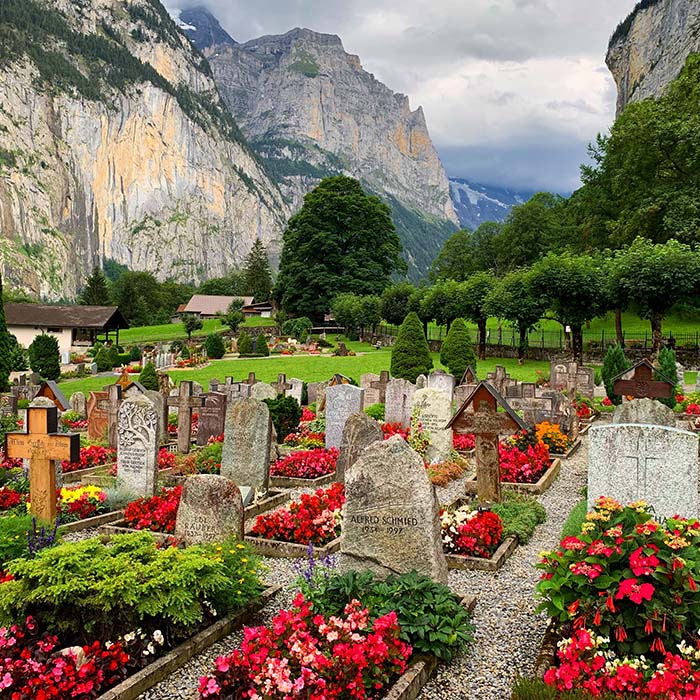 a beautiful cemetary with colourfu; flower beds tucked between the mountains